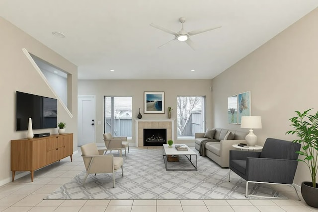 living room featuring light tile patterned floors, ceiling fan, baseboards, and a tiled fireplace