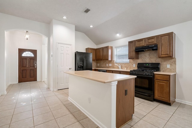 kitchen with light tile patterned floors, decorative backsplash, vaulted ceiling, black appliances, and a center island