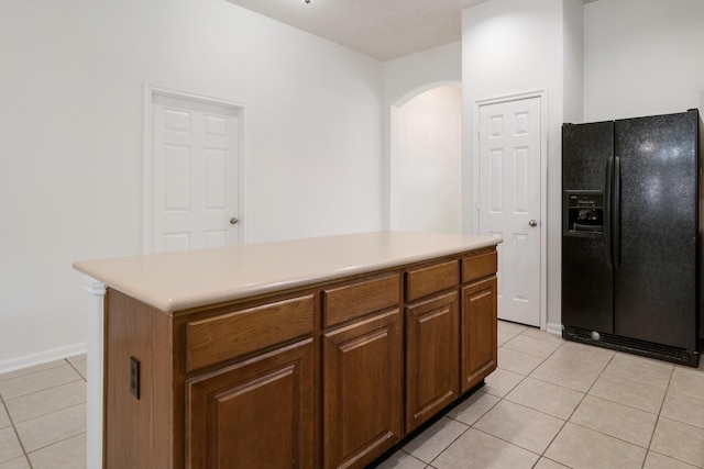 kitchen with black refrigerator with ice dispenser, light tile patterned floors, and a center island