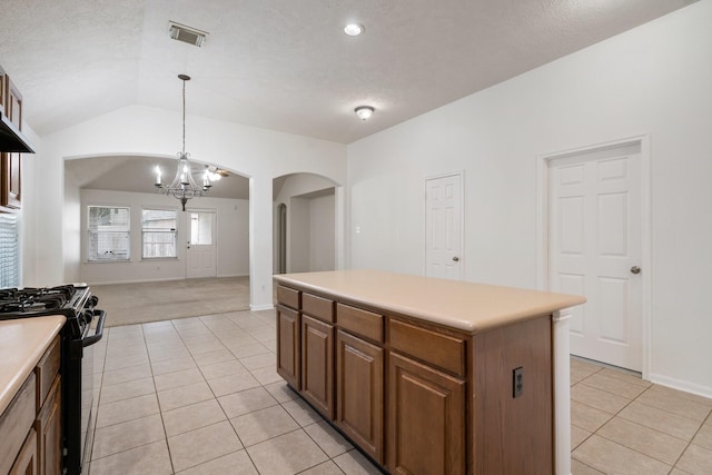 kitchen featuring decorative light fixtures, light tile patterned flooring, black gas range oven, and a kitchen island