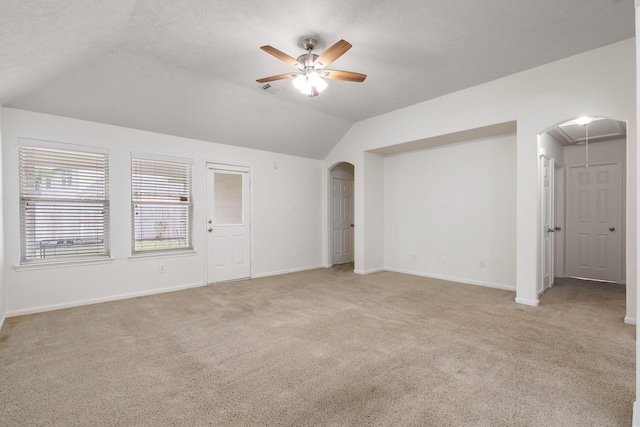 carpeted spare room with vaulted ceiling, ceiling fan, and a textured ceiling