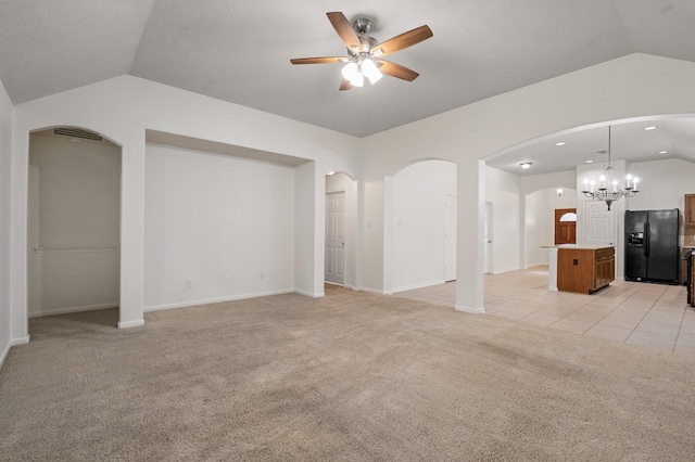 unfurnished living room with ceiling fan with notable chandelier, light carpet, and vaulted ceiling