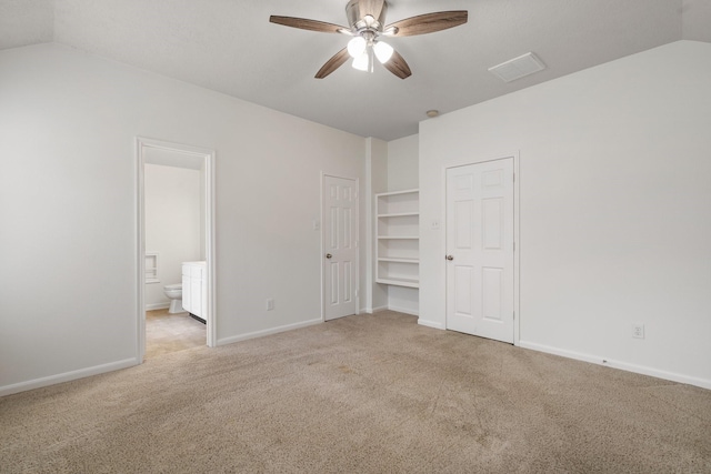 unfurnished bedroom featuring ceiling fan, light carpet, ensuite bath, and vaulted ceiling