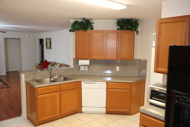 kitchen with sink, decorative backsplash, light tile patterned floors, white dishwasher, and black refrigerator with ice dispenser