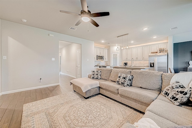 living room with light hardwood / wood-style floors, sink, and ceiling fan