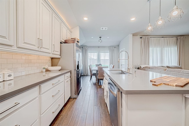 kitchen featuring sink, white cabinets, a center island with sink, decorative backsplash, and stainless steel appliances