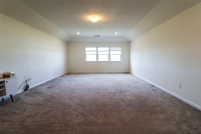 carpeted spare room with vaulted ceiling