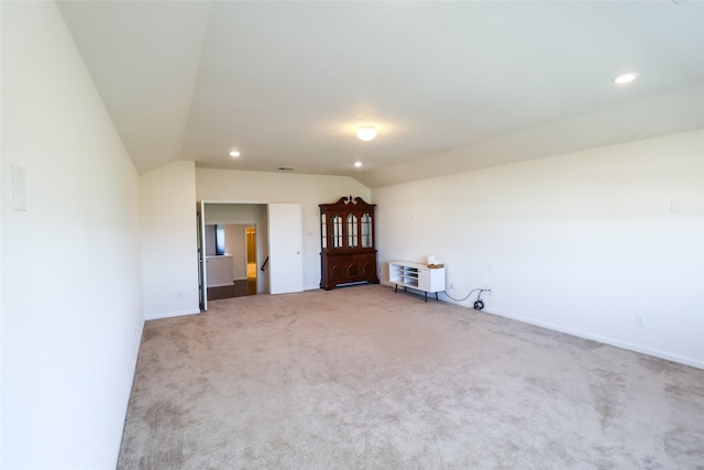 carpeted empty room with heating unit and vaulted ceiling