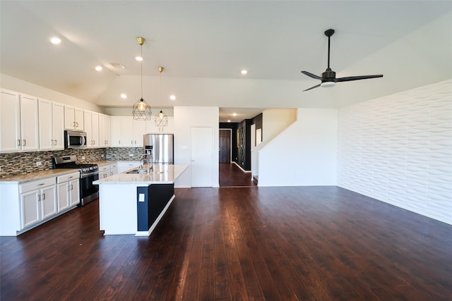 kitchen with lofted ceiling, decorative backsplash, an island with sink, stainless steel appliances, and white cabinets