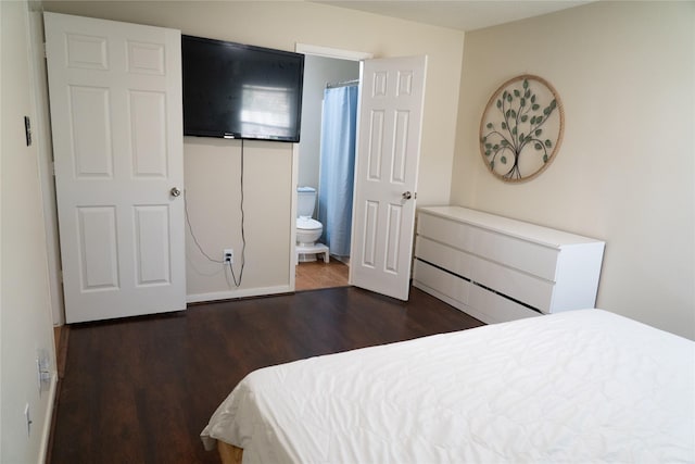 bedroom with dark wood-type flooring and connected bathroom