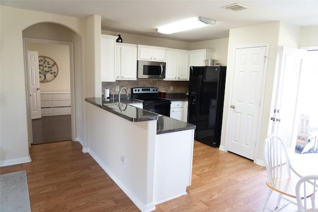 kitchen featuring black appliances, white cabinets, decorative backsplash, kitchen peninsula, and light wood-type flooring