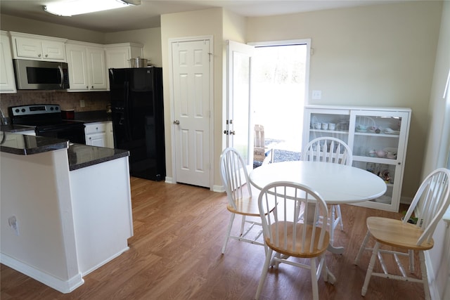 kitchen featuring decorative backsplash, black refrigerator with ice dispenser, range with electric cooktop, and white cabinets