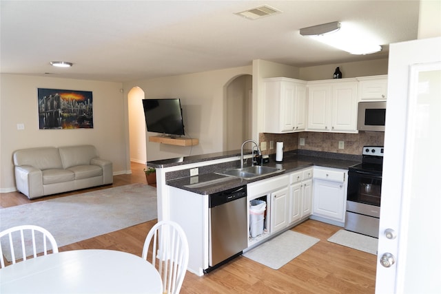 kitchen with sink, white cabinetry, light wood-type flooring, appliances with stainless steel finishes, and kitchen peninsula