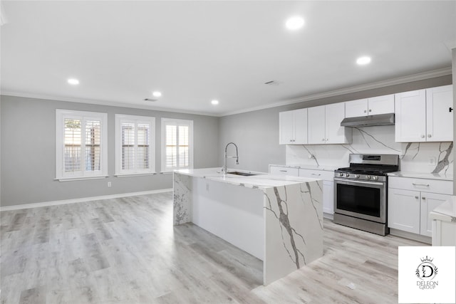 kitchen featuring an island with sink, stainless steel range with gas cooktop, crown molding, and white cabinetry