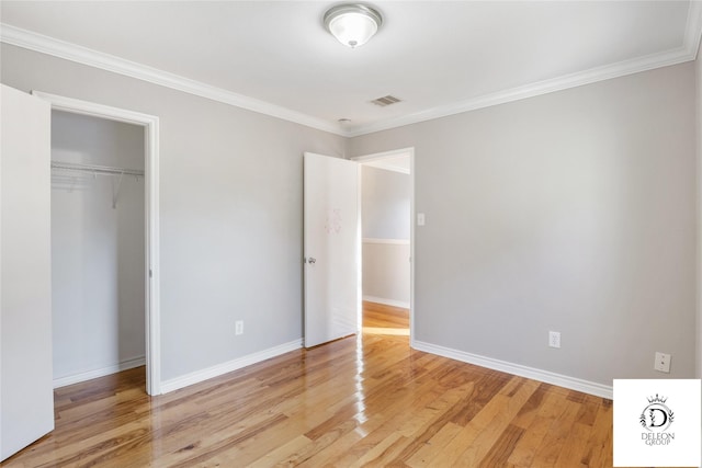 unfurnished bedroom featuring a closet, crown molding, and light hardwood / wood-style floors