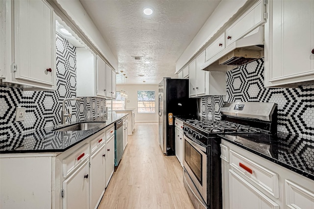 kitchen featuring backsplash, sink, white cabinetry, stainless steel appliances, and dark stone counters