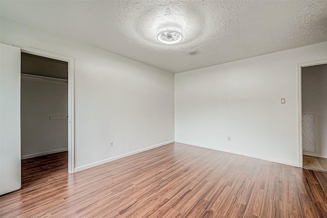 spare room with a textured ceiling and light hardwood / wood-style flooring