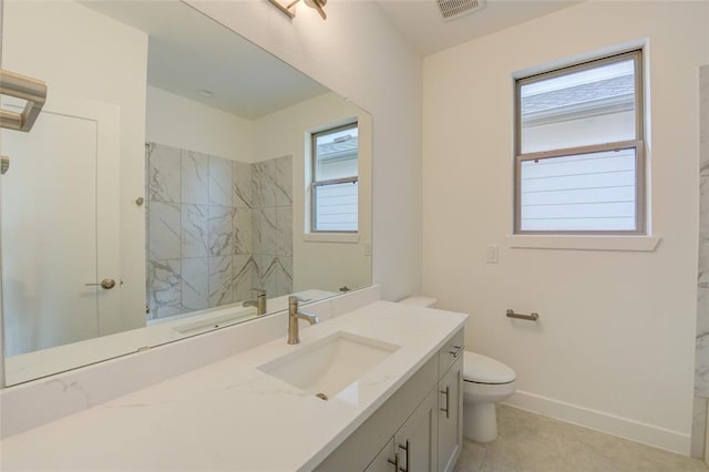 bathroom featuring toilet, vanity, a tile shower, and tile patterned flooring