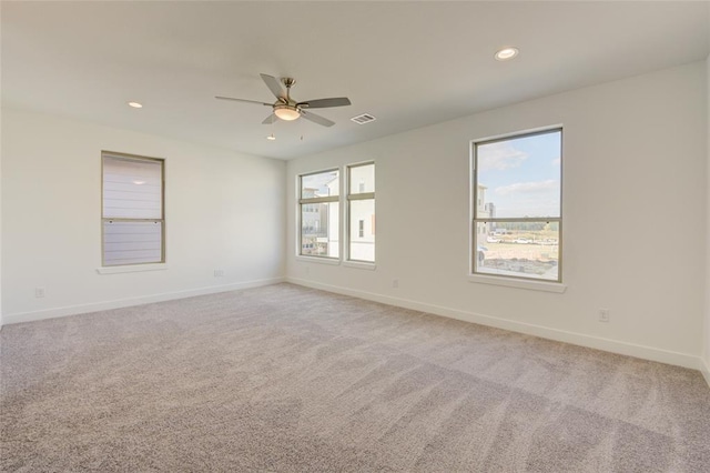 spare room featuring light carpet, a healthy amount of sunlight, and ceiling fan