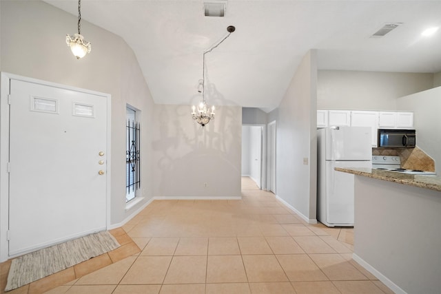 foyer entrance featuring vaulted ceiling, a notable chandelier, and light tile patterned flooring