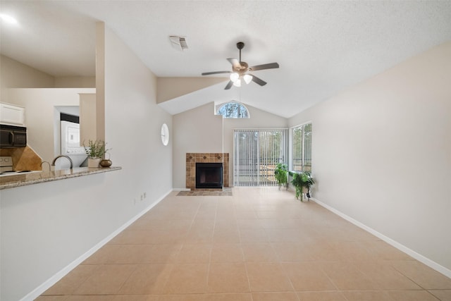 unfurnished living room featuring vaulted ceiling, ceiling fan, light tile patterned floors, and a fireplace