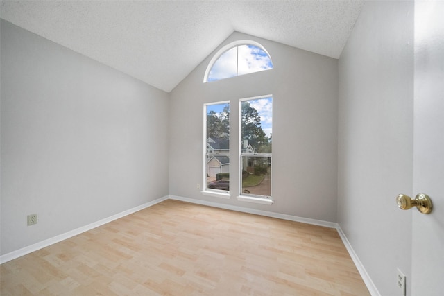 unfurnished room featuring light wood-type flooring, vaulted ceiling, and a textured ceiling