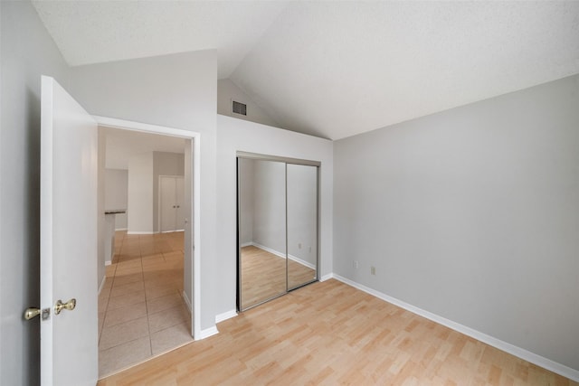 unfurnished bedroom featuring a closet, lofted ceiling, and light hardwood / wood-style floors