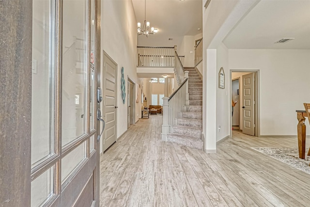 entryway featuring a towering ceiling, an inviting chandelier, and light hardwood / wood-style flooring