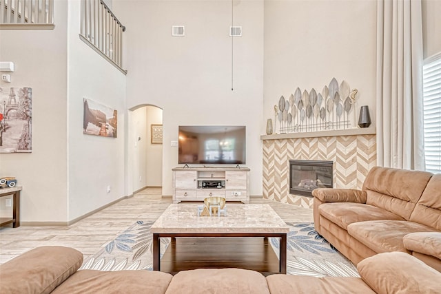 living room with light hardwood / wood-style flooring, a towering ceiling, and a fireplace