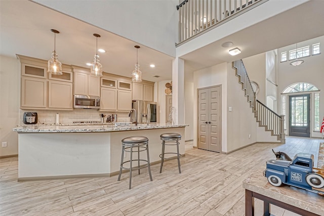 kitchen featuring stainless steel appliances, pendant lighting, decorative backsplash, and light stone counters