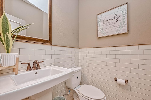 bathroom featuring sink, tile walls, and toilet