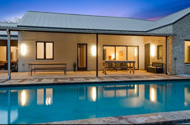 pool at dusk featuring a patio area