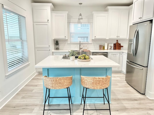 kitchen featuring stainless steel appliances, pendant lighting, and white cabinets