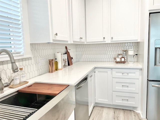 kitchen featuring stainless steel appliances, white cabinets, tasteful backsplash, and light stone countertops