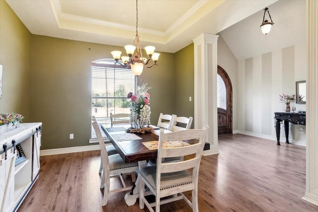 dining room featuring an inviting chandelier, light hardwood / wood-style flooring, and a raised ceiling