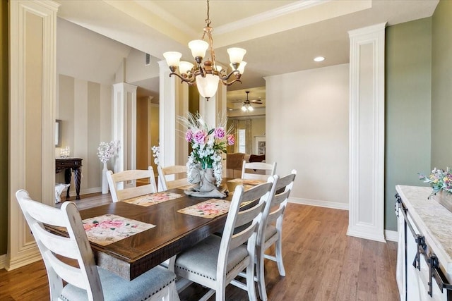 dining room with a raised ceiling, light wood-type flooring, and ceiling fan