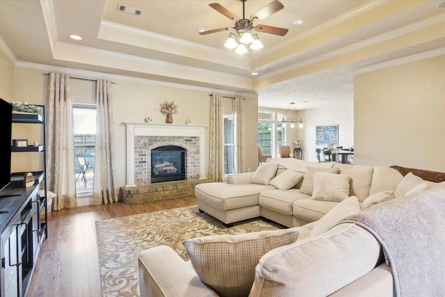 living room with wood-type flooring, a tray ceiling, a wealth of natural light, and crown molding