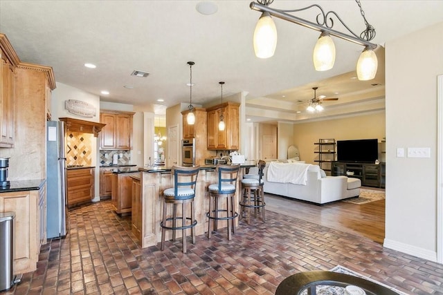 kitchen with stainless steel appliances, tasteful backsplash, a kitchen breakfast bar, hanging light fixtures, and ceiling fan