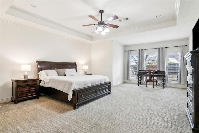 carpeted bedroom with ceiling fan, ornamental molding, and a raised ceiling