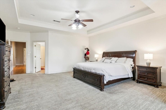 bedroom featuring light carpet, ceiling fan, crown molding, and a tray ceiling