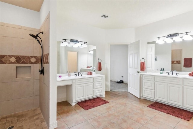 bathroom with tiled shower, vanity, and tile patterned flooring