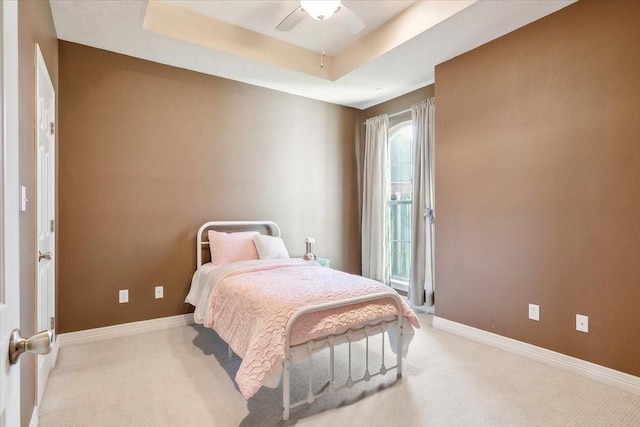 bedroom featuring ceiling fan, light colored carpet, and a raised ceiling