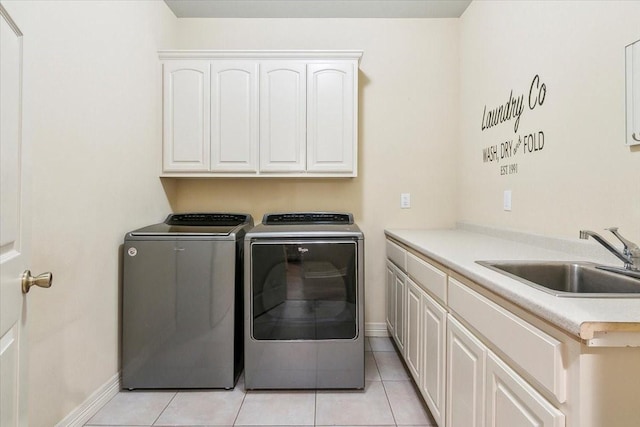 laundry room with light tile patterned floors, sink, washing machine and clothes dryer, and cabinets