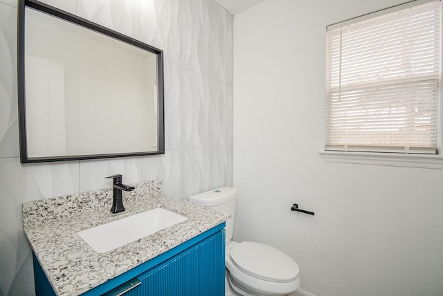 bathroom with toilet, tile walls, and vanity