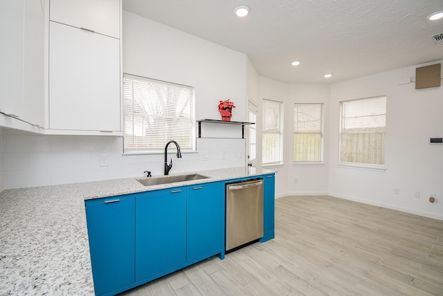 kitchen with light stone countertops, dishwasher, light hardwood / wood-style floors, sink, and blue cabinets