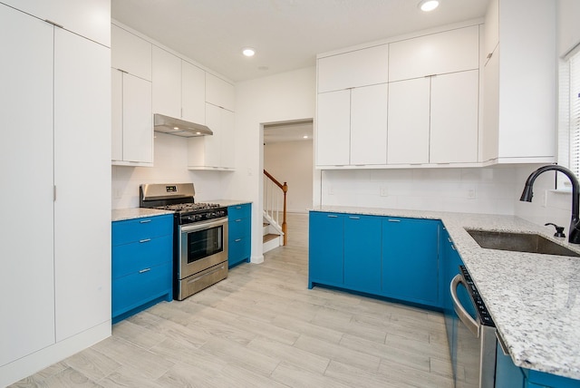 kitchen with blue cabinetry, stainless steel appliances, white cabinets, and sink