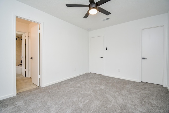 unfurnished bedroom featuring light carpet, ceiling fan, and connected bathroom