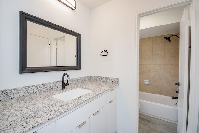 full bathroom featuring toilet, tiled shower / bath, vanity, and hardwood / wood-style flooring