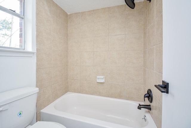 bathroom featuring toilet and tiled shower / bath