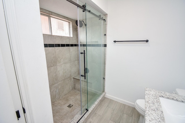 bathroom featuring toilet, an enclosed shower, and vanity